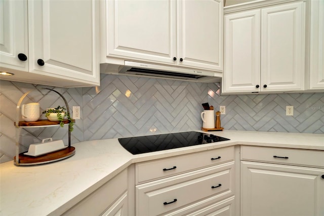 kitchen featuring white cabinets, decorative backsplash, black electric cooktop, and range hood