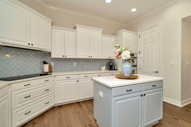 kitchen featuring ornamental molding, black electric stovetop, light wood-style flooring, and a center island