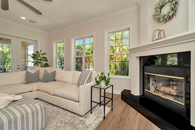 living area with recessed lighting, ornamental molding, a glass covered fireplace, wood finished floors, and baseboards