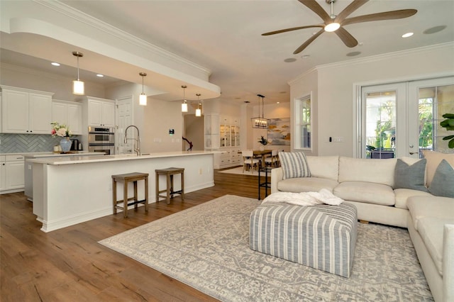 living area featuring ceiling fan, recessed lighting, dark wood-type flooring, ornamental molding, and french doors