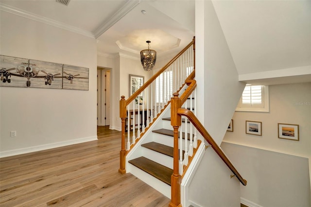 stairs with crown molding, visible vents, an inviting chandelier, wood finished floors, and baseboards