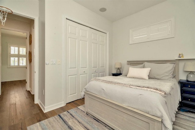 bedroom with a closet, wood finished floors, and baseboards