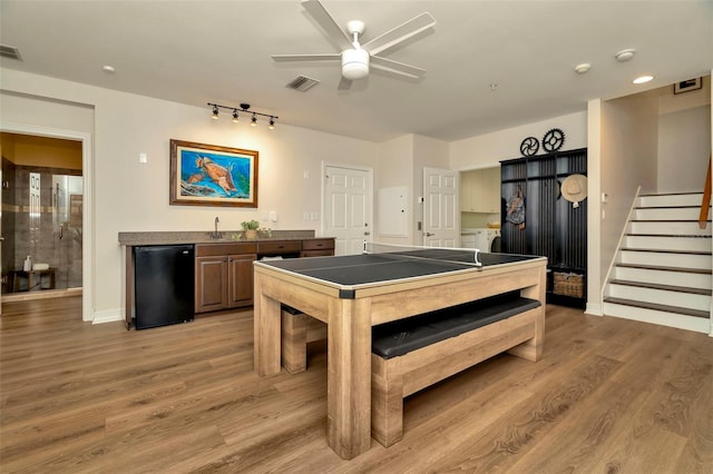 recreation room featuring light wood finished floors, visible vents, baseboards, ceiling fan, and wet bar