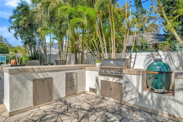 view of patio / terrace featuring a grill, fence, an outdoor kitchen, and outdoor dry bar