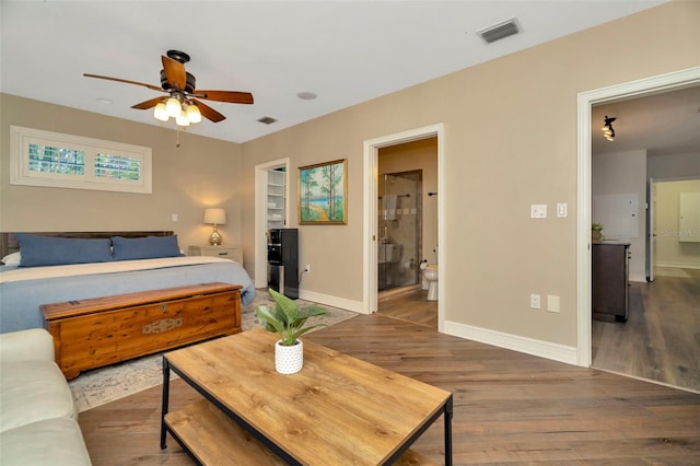 bedroom featuring connected bathroom, wood finished floors, visible vents, and baseboards