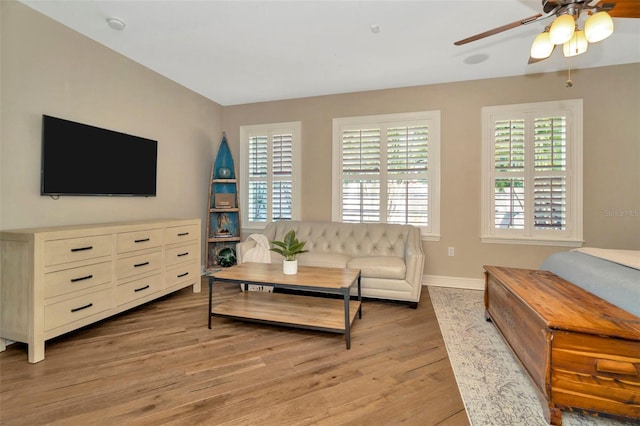 living room with baseboards, ceiling fan, light wood-style floors, and a healthy amount of sunlight