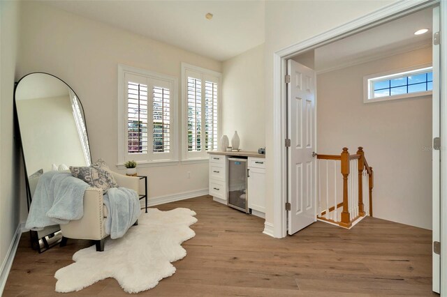 living area featuring wine cooler, an upstairs landing, light wood-style flooring, and baseboards