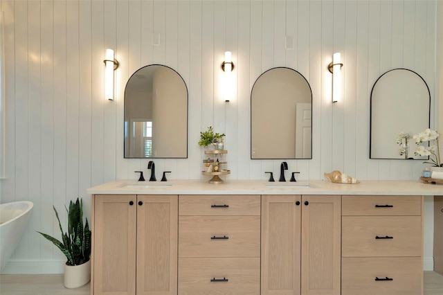 full bathroom featuring double vanity, a freestanding tub, and a sink