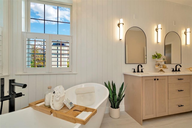 bathroom with a soaking tub, a sink, and double vanity