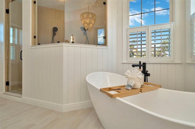 bathroom featuring wood finished floors, a freestanding tub, and a shower stall