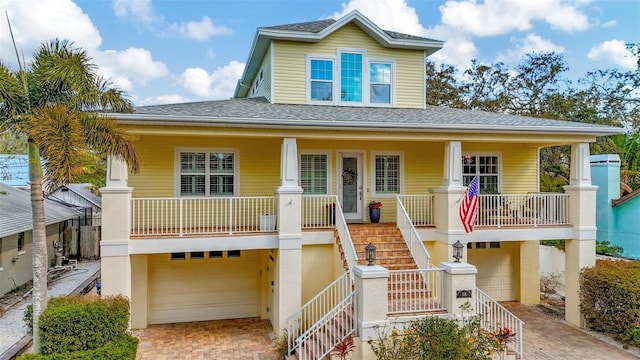 view of front of house featuring a porch, a garage, stairway, decorative driveway, and stucco siding