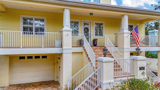 doorway to property featuring covered porch, an attached garage, and stucco siding