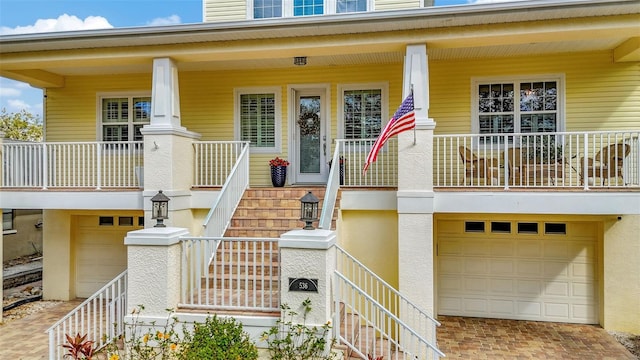 entrance to property with covered porch, a garage, and stucco siding