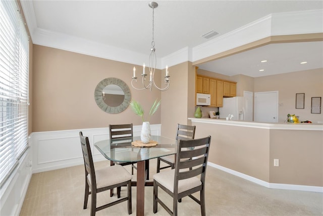 dining area featuring a chandelier, visible vents, wainscoting, and ornamental molding