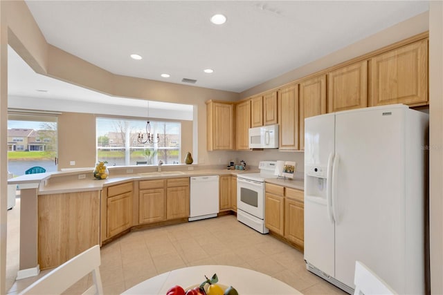 kitchen with light brown cabinetry, visible vents, white appliances, and a sink