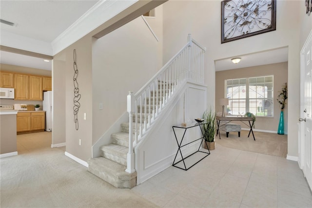 stairs featuring visible vents, baseboards, tile patterned flooring, crown molding, and carpet flooring