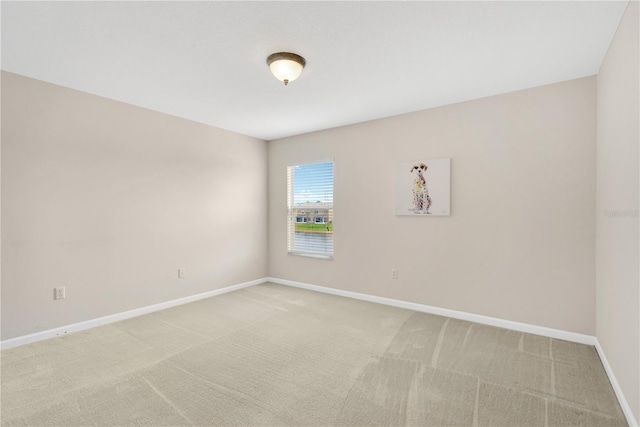 empty room featuring light colored carpet and baseboards