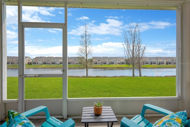 sunroom / solarium featuring a water view and a residential view