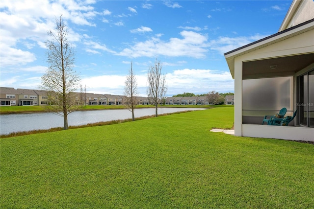 view of yard featuring a residential view, a water view, and a sunroom