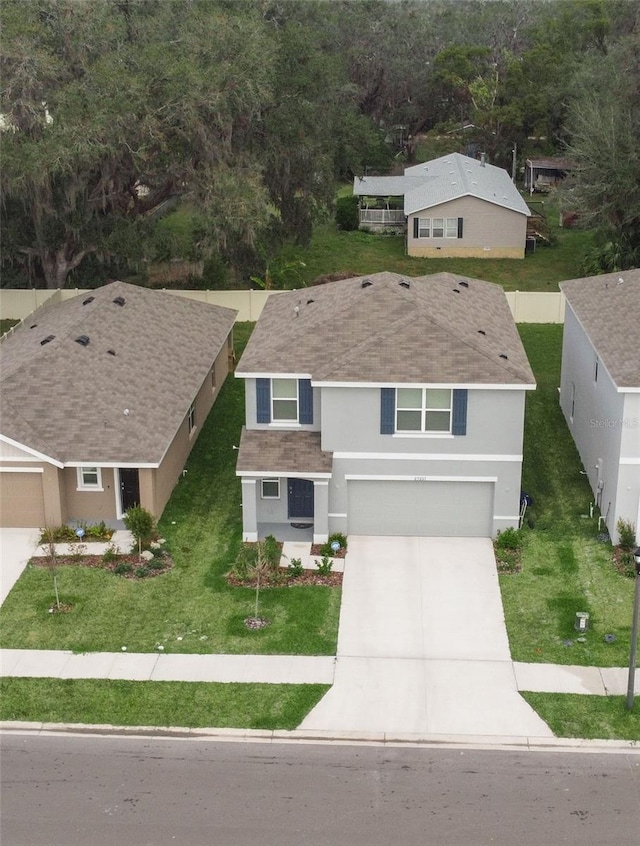 view of front of home with a garage, concrete driveway, a front lawn, and stucco siding