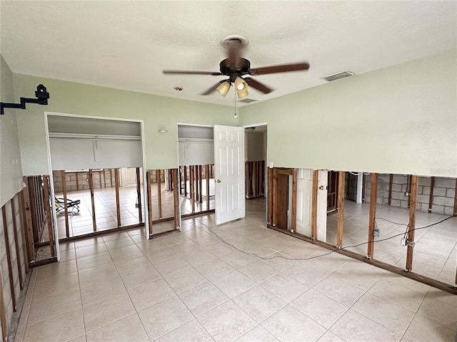 spare room with a textured ceiling, light tile patterned flooring, visible vents, and a ceiling fan