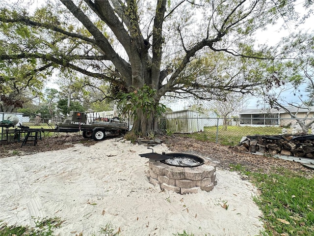 view of yard featuring an outdoor fire pit and fence