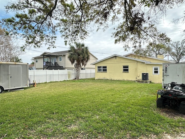 view of yard featuring a storage unit, fence, central AC, and an outbuilding