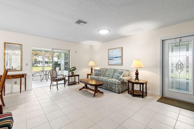 living area with visible vents, a textured ceiling, baseboards, and light tile patterned flooring