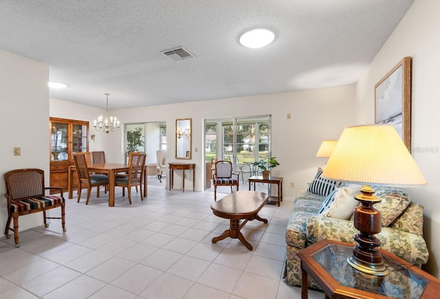 living area with light tile patterned floors, a textured ceiling, visible vents, and an inviting chandelier