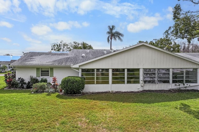 back of property with a yard, roof with shingles, and a sunroom