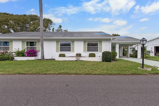 single story home with driveway, a front lawn, an attached carport, and stucco siding