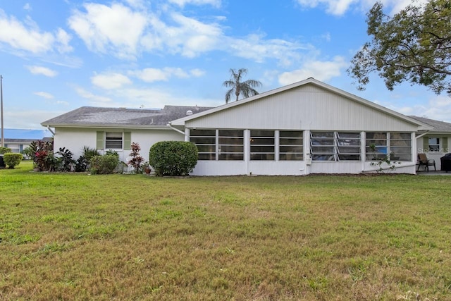 back of house with a sunroom and a lawn