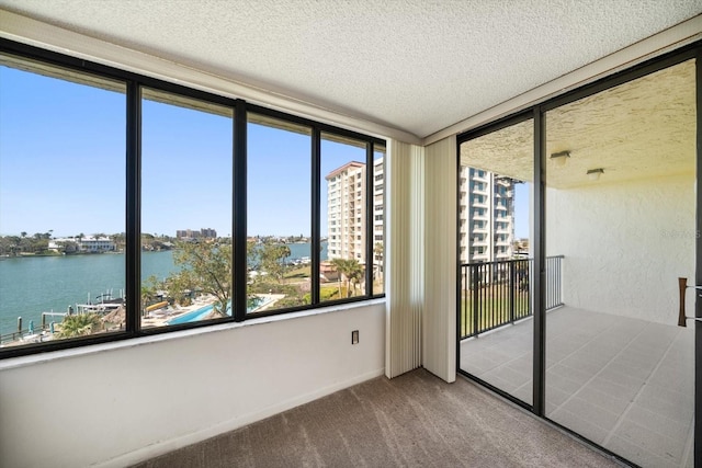 empty room featuring a water view, carpet, and a textured ceiling