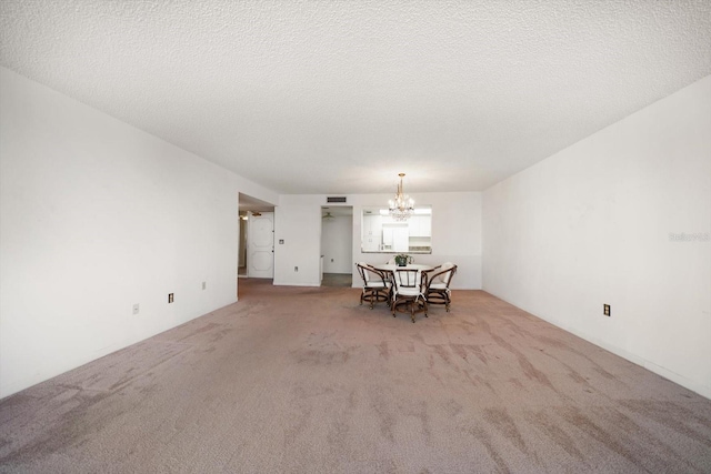 unfurnished dining area featuring a chandelier, a textured ceiling, and carpet