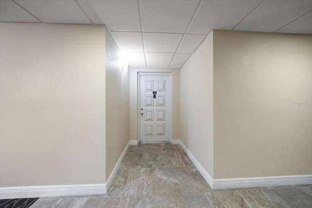 hall featuring baseboards and a drop ceiling