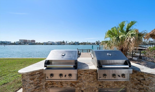 view of patio / terrace with exterior kitchen, a water view, and a grill