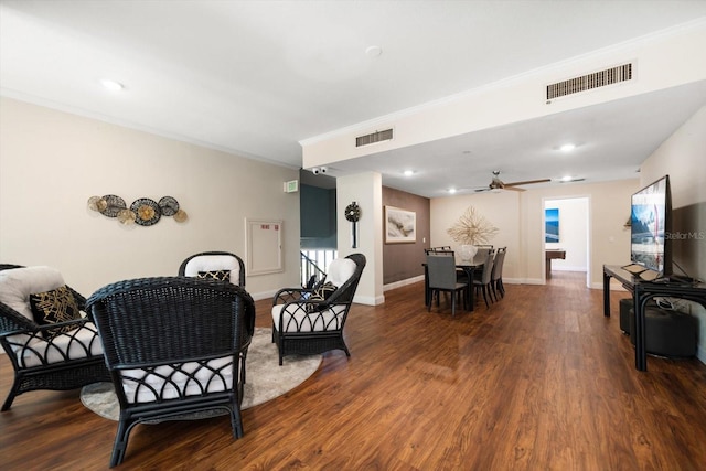 living area with baseboards, visible vents, wood finished floors, and ornamental molding