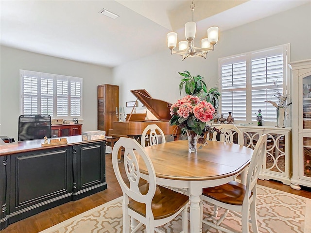 dining room featuring dark wood-style floors, a chandelier, visible vents, and a healthy amount of sunlight