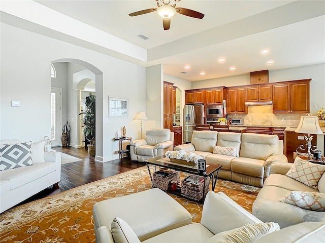 living area featuring visible vents, arched walkways, baseboards, dark wood-style floors, and recessed lighting