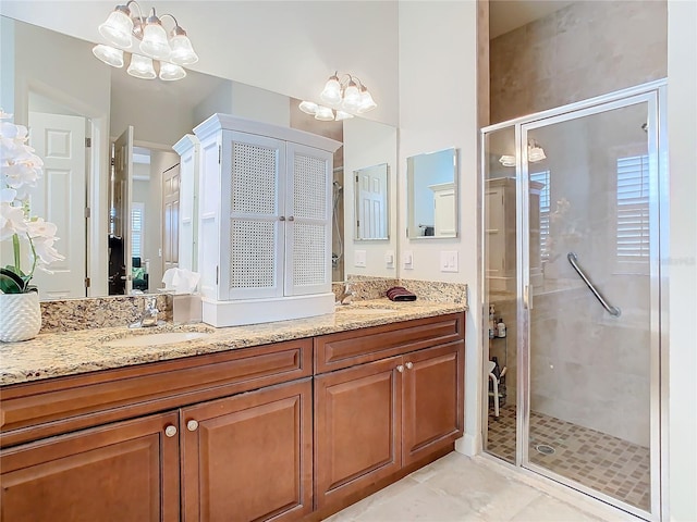 bathroom featuring an inviting chandelier, a shower stall, and vanity