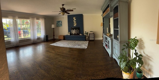 living area with a brick fireplace, baseboards, ornamental molding, wood finished floors, and a ceiling fan