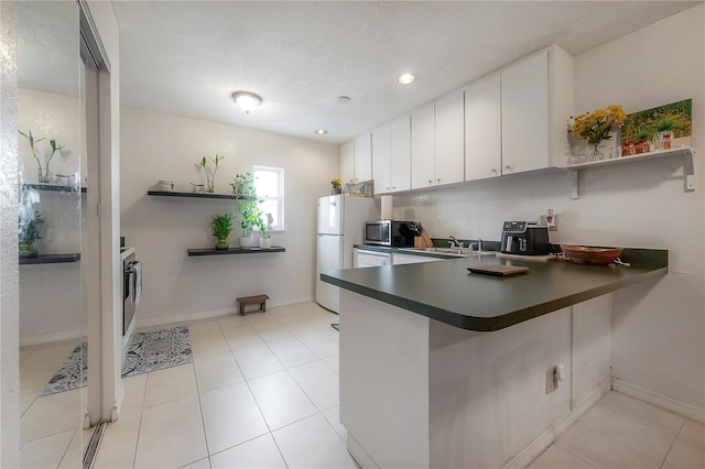 kitchen with a peninsula, white cabinets, open shelves, stainless steel microwave, and dark countertops