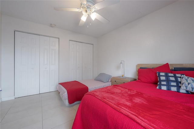 bedroom with light tile patterned floors, ceiling fan, and two closets