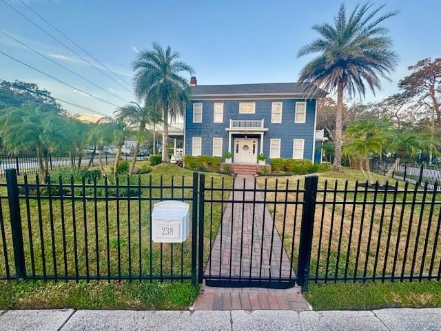 view of gate featuring a fenced front yard and a lawn