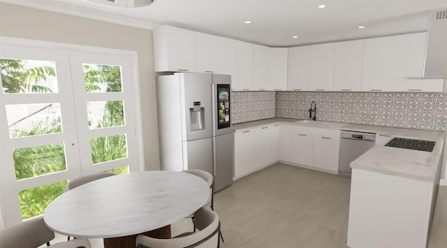 kitchen with stainless steel appliances, a sink, white cabinets, backsplash, and light wood finished floors