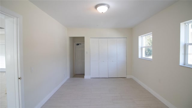 unfurnished bedroom featuring a closet, light wood-style flooring, and baseboards