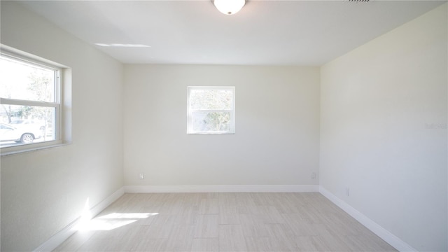 unfurnished room featuring light wood-style floors, plenty of natural light, and baseboards