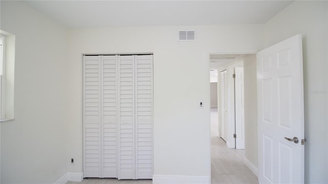 unfurnished bedroom with a closet, visible vents, and baseboards