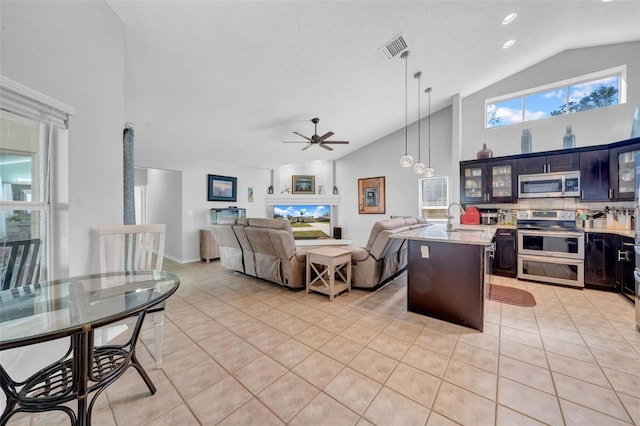 kitchen featuring visible vents, glass insert cabinets, appliances with stainless steel finishes, hanging light fixtures, and a sink