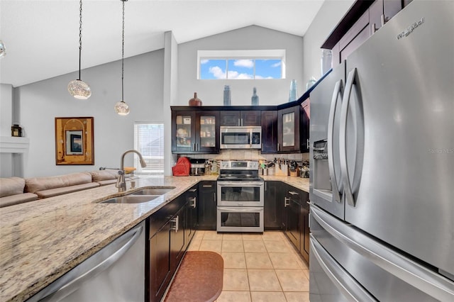 kitchen with light stone counters, glass insert cabinets, decorative light fixtures, stainless steel appliances, and a sink